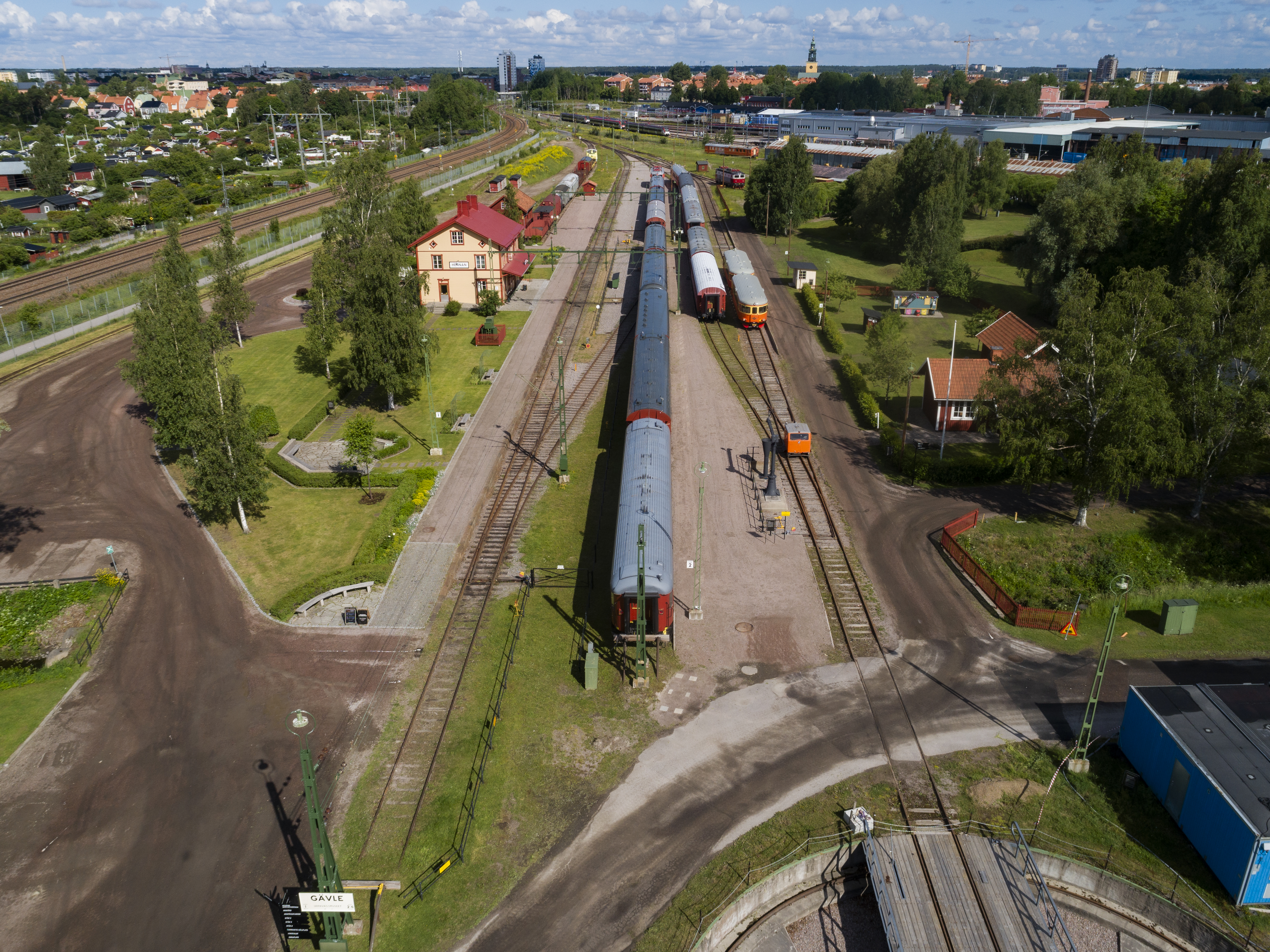Järnvägsparken ovanifrån. Ett gult stationshus, grönområde och spårväg.