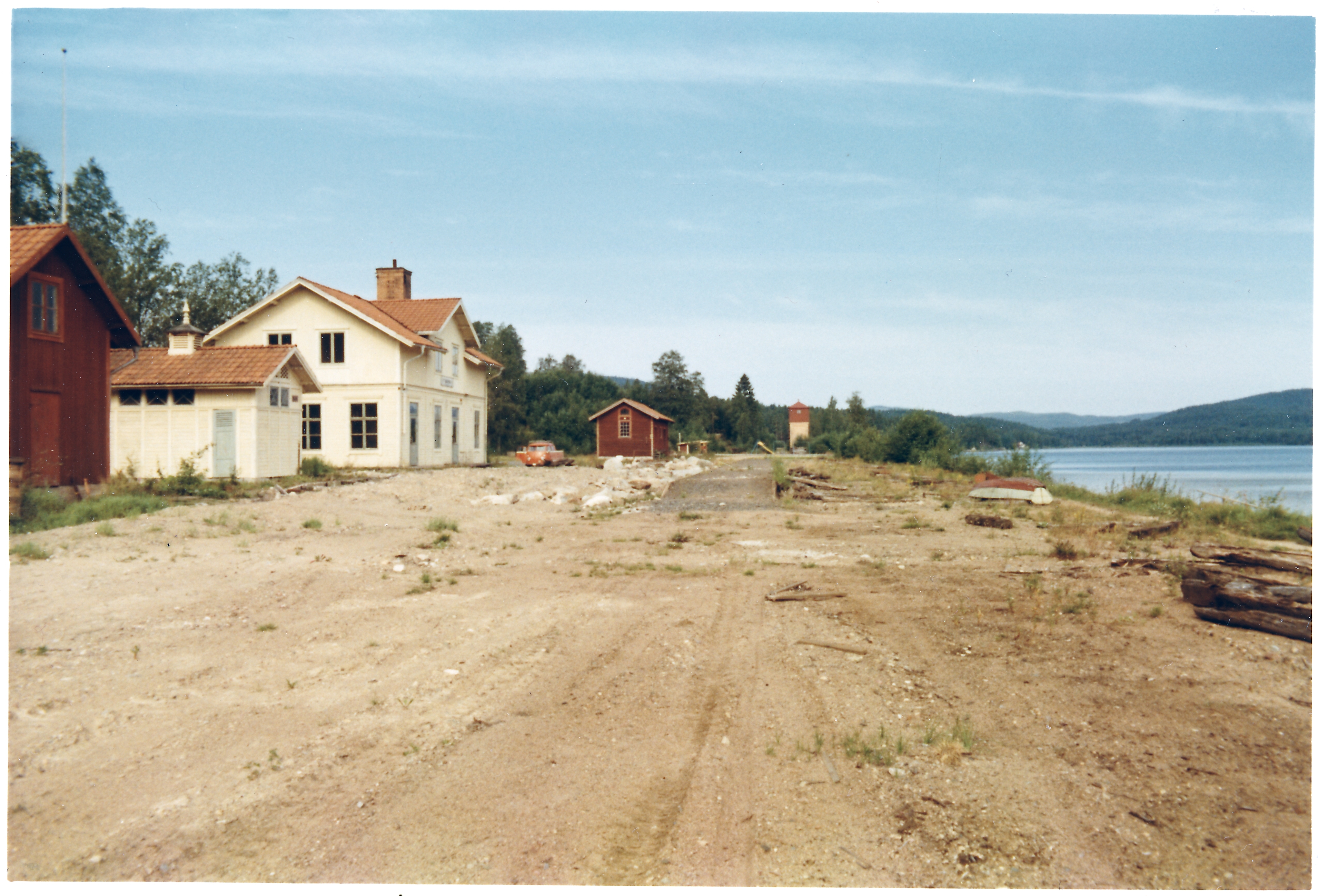 Vitt stationshus med omkringliggande byggnader utan järnvägsspår. Sågmyra järnvägsstation, stationen är nedlagd och spåren är upprivna.