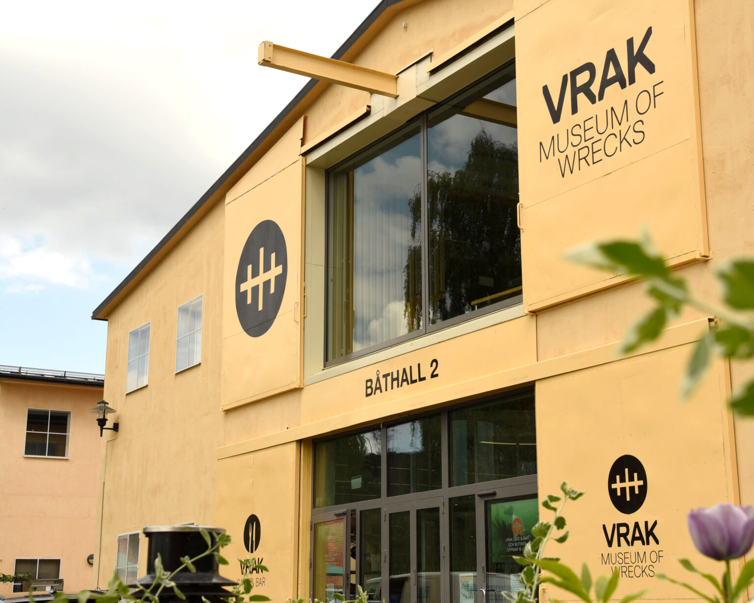 Vrak - Museum of Wrecks gula fasad framför en gråmulen himmel.