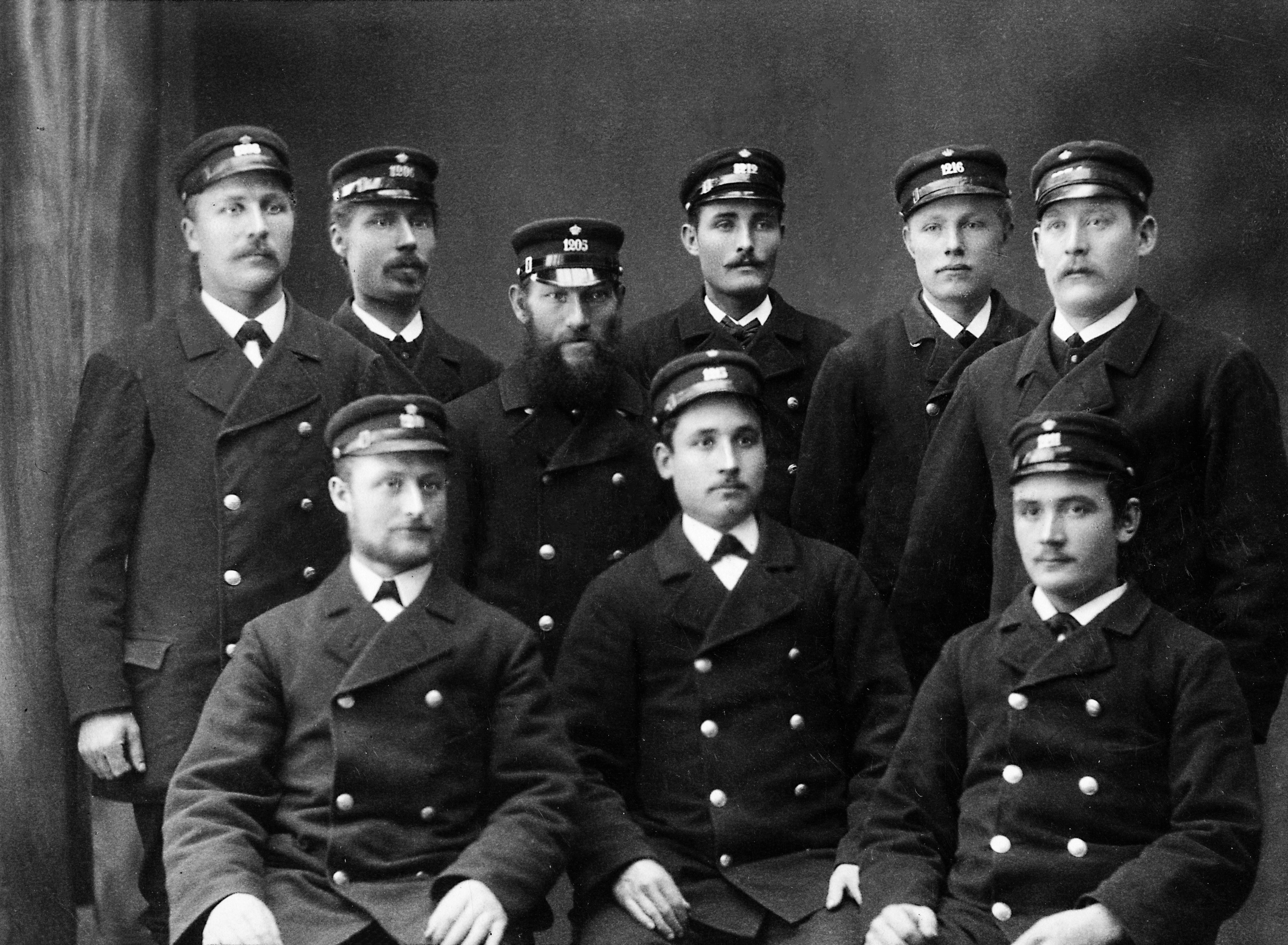 Nio män i uniform uppställda för fotografering.