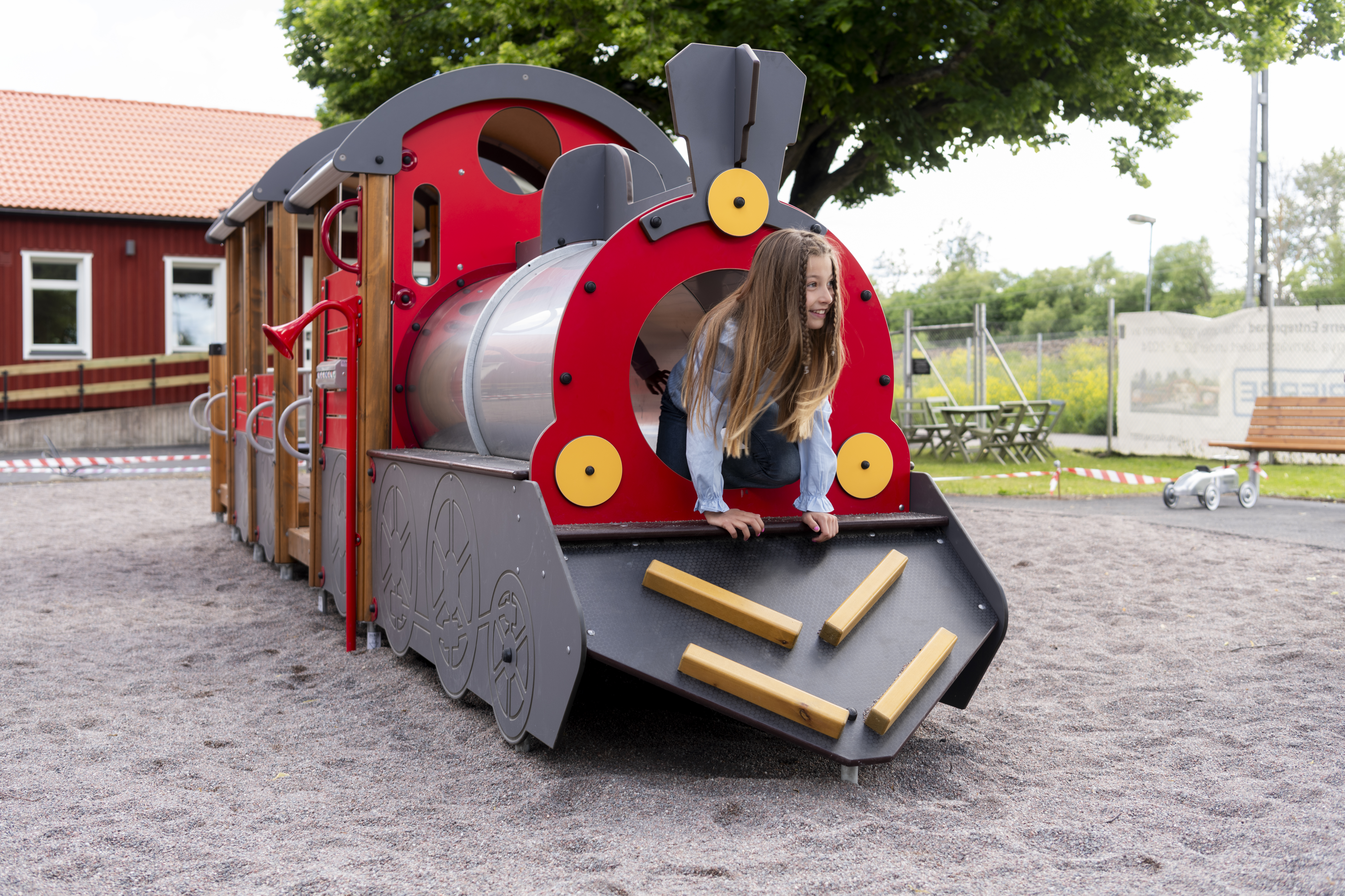 A child is looking out of a train at a playground.