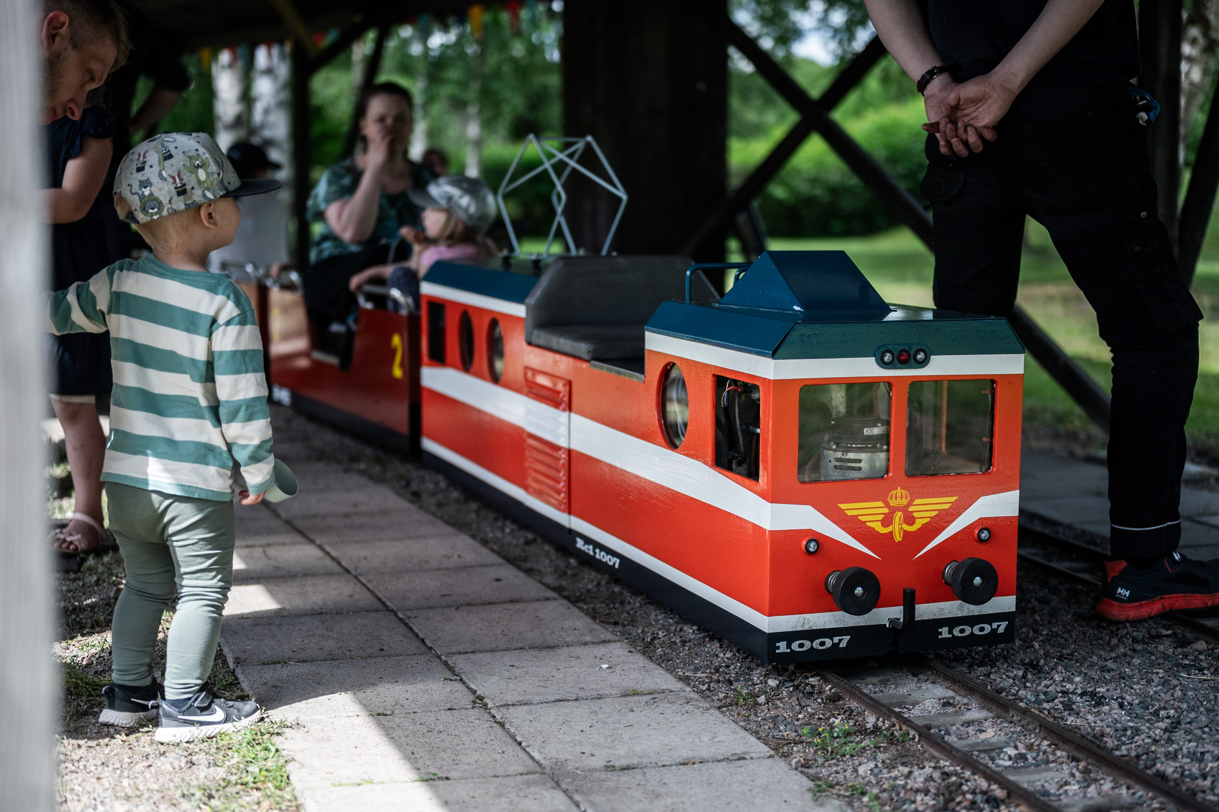 A child is standing there waiting to board a miniature train.
