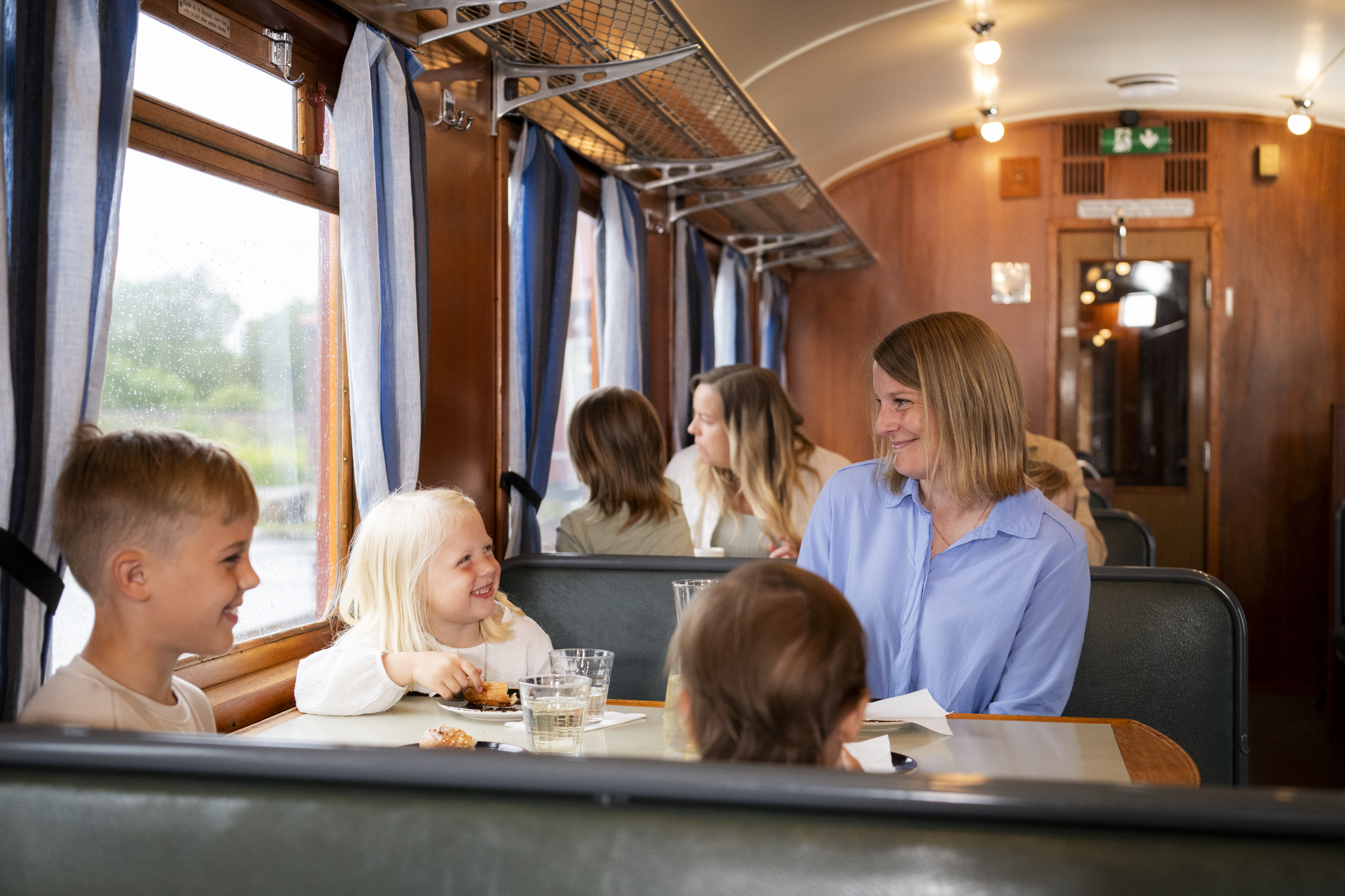 A mother and her children are sitting having a coffee in a restaurant carriage at the Railway Museum.
