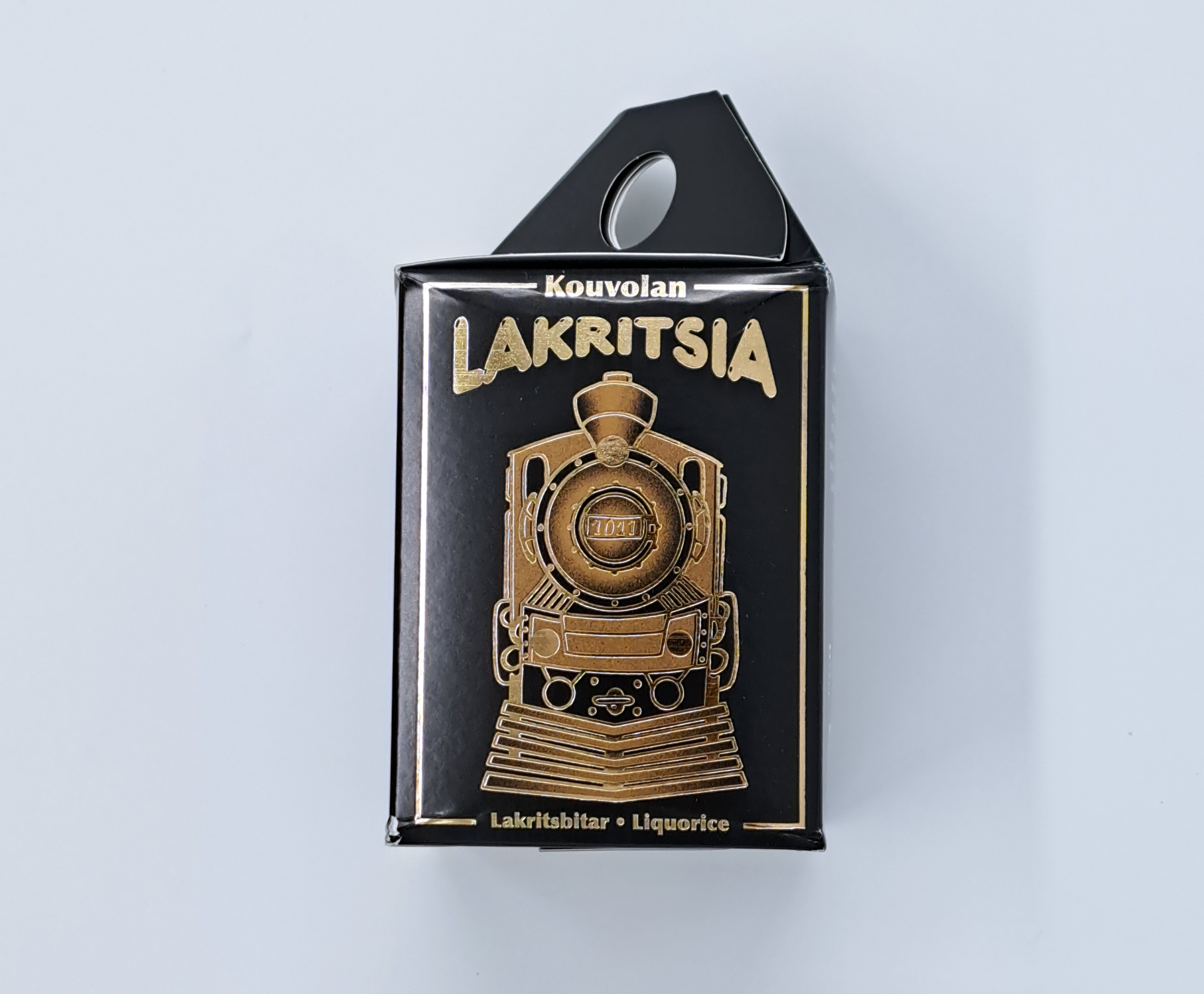 Svart box med tågmotiv och texten Kouvlan lakrits.