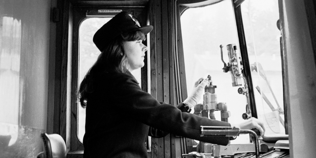 Kvinnlig konduktör i förarhytt.