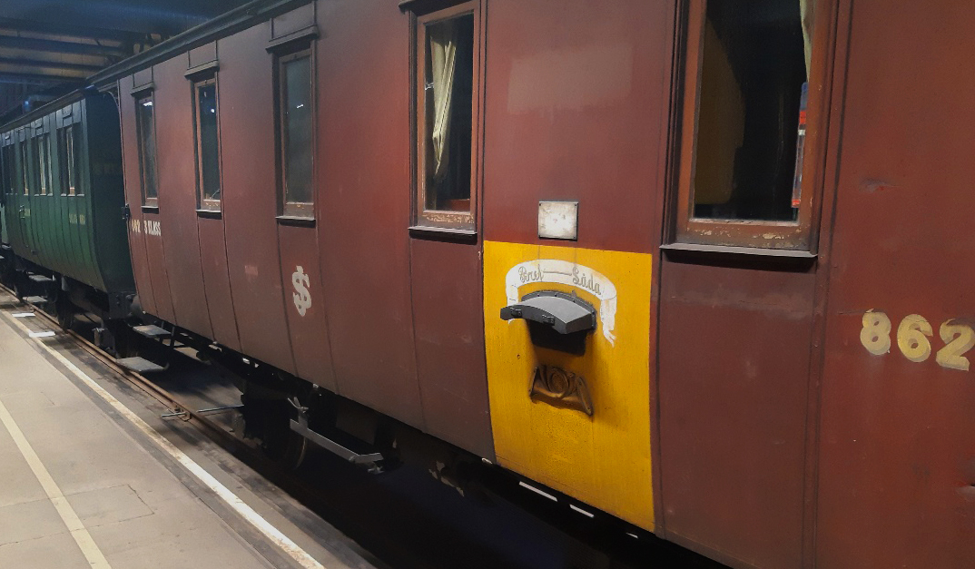 A maroon mail carriage stands in an exhibition hall.