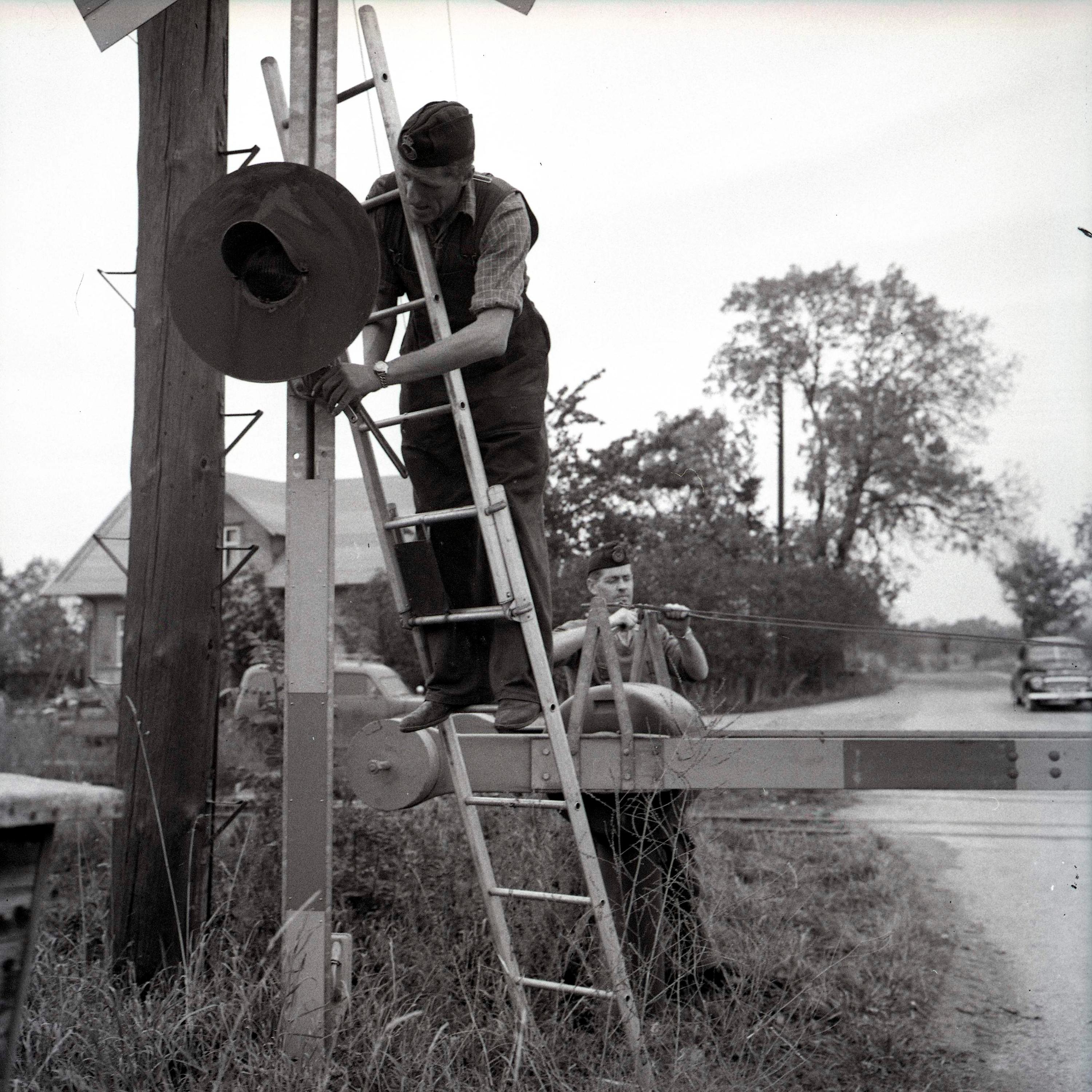 A black and white photo of a worker taking down a railway boom and signals on the Öland Railway.