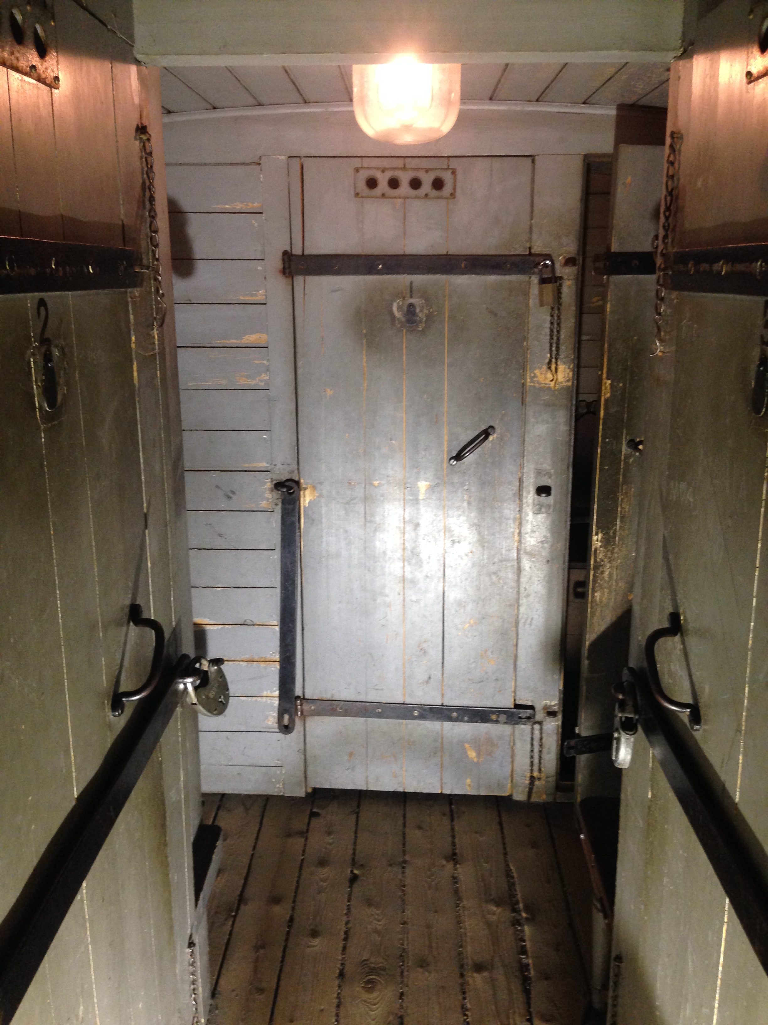 Interiör av fångvagn från 1968, UWHJ E1 från 1868. På sidorna av korridoren syns dörrar till enmanscellerna, rakt fram den större cellen med plats för upp till 5 personer.