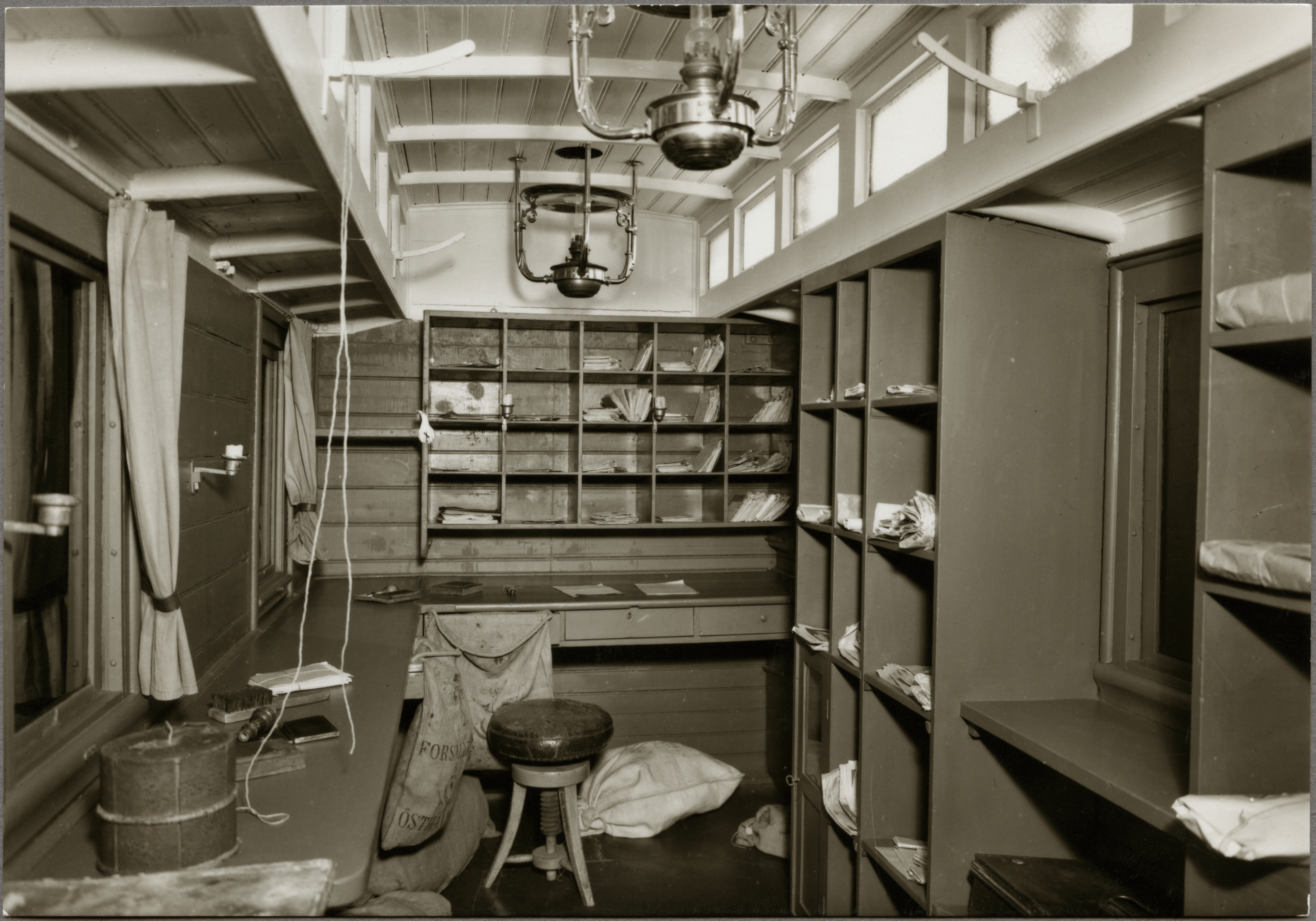 Interiör av järnvägspostvagn 1870-talet, väggar med hyllor och fack.