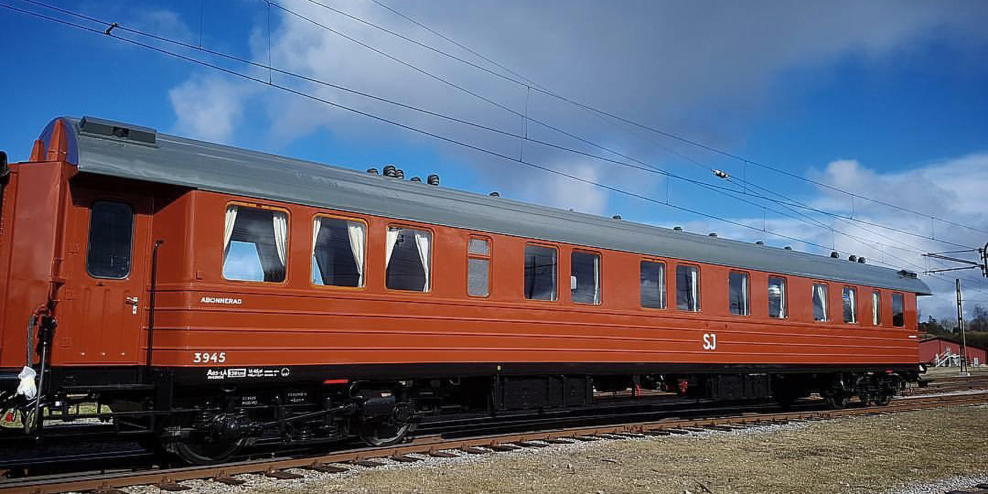 Roströd personvagn placerad på spårområde.