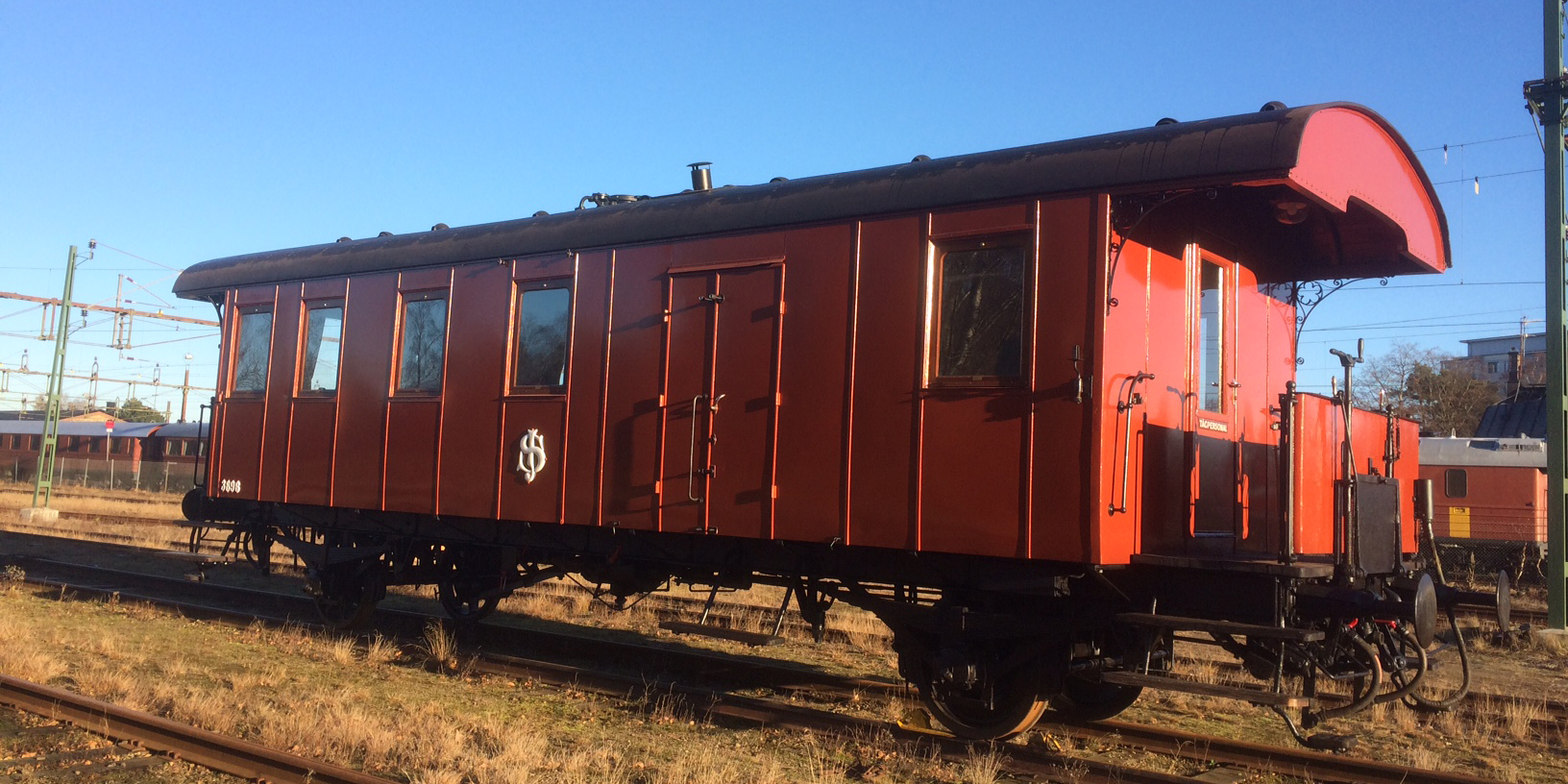 Rust red train carriage with a protruding platform at the back placed in the station area.