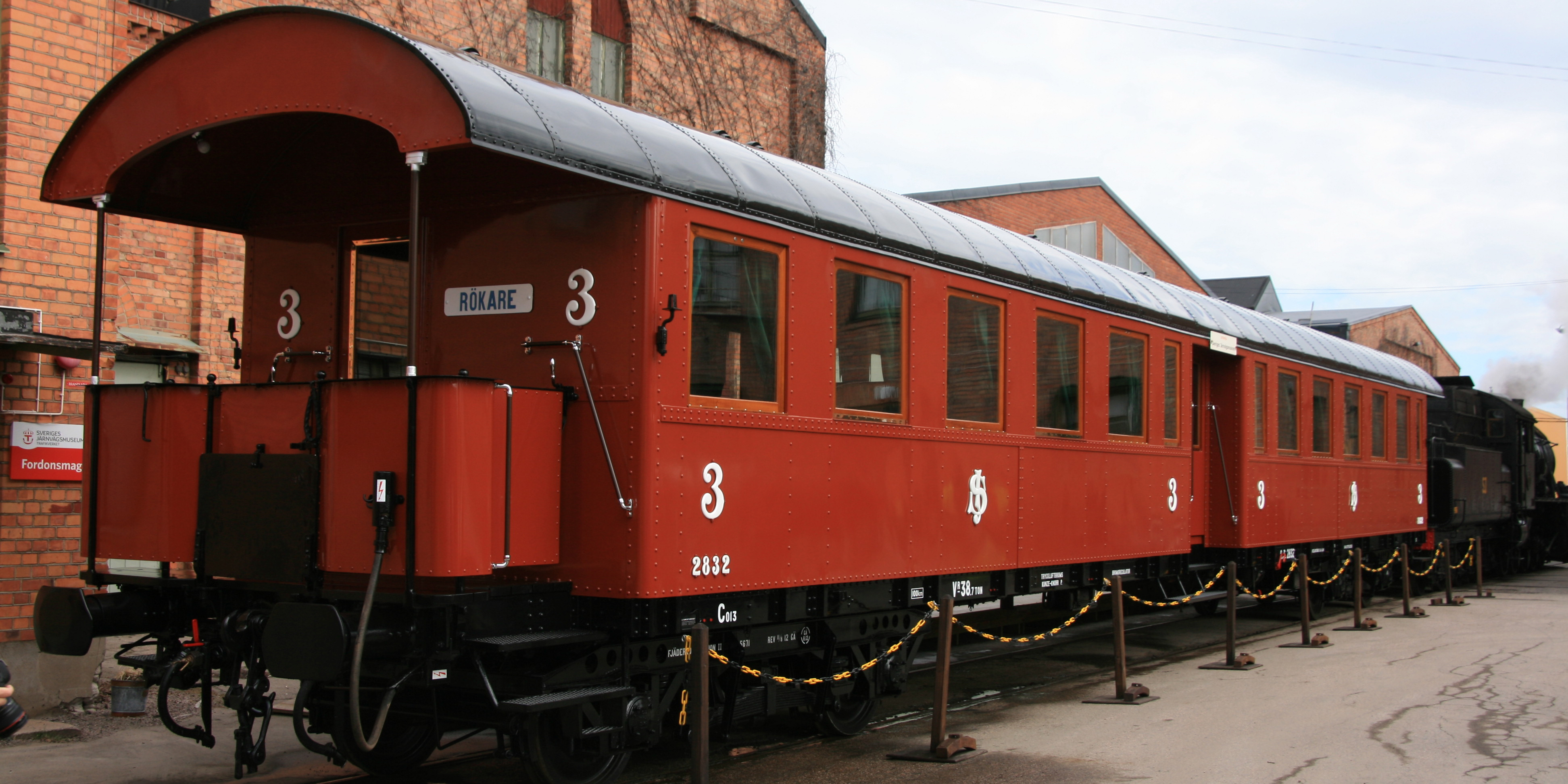 Rust red train carriage with a protruding platform at the back placed in the station area.