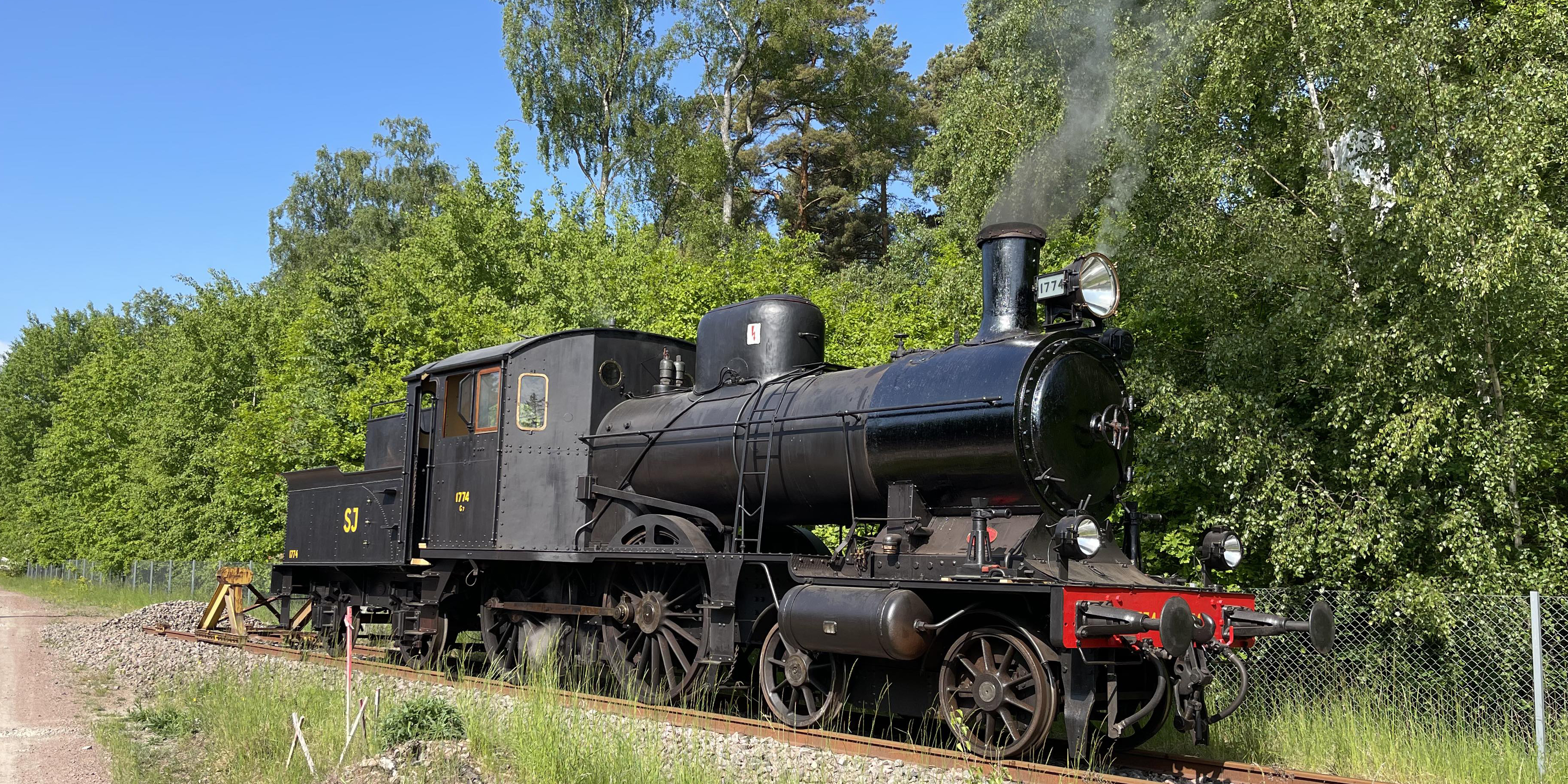 Black locomotive standing on rails on a summer day.